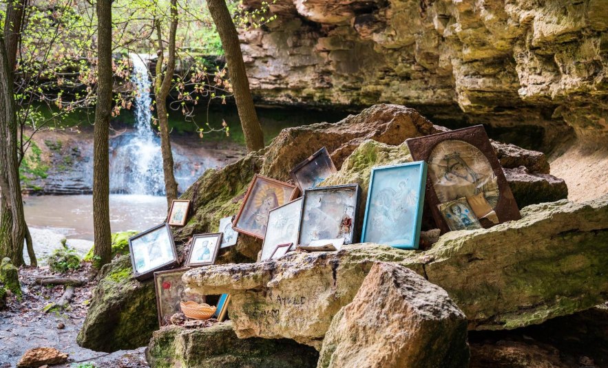 A small waterfall in a rocky forest with framed photos set on the stones